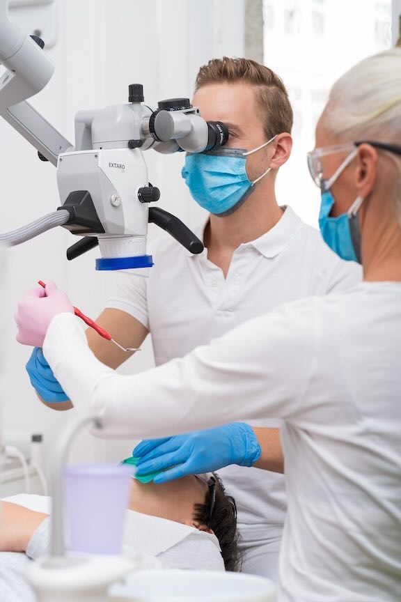 Zahnarzt am Mikroskop bei der Wurzelbehandlung